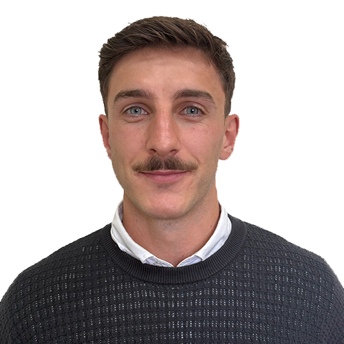 Portrait of a man with short brown hair and a mustache, wearing a dark knitted sweater over a white collared shirt, against a white background.